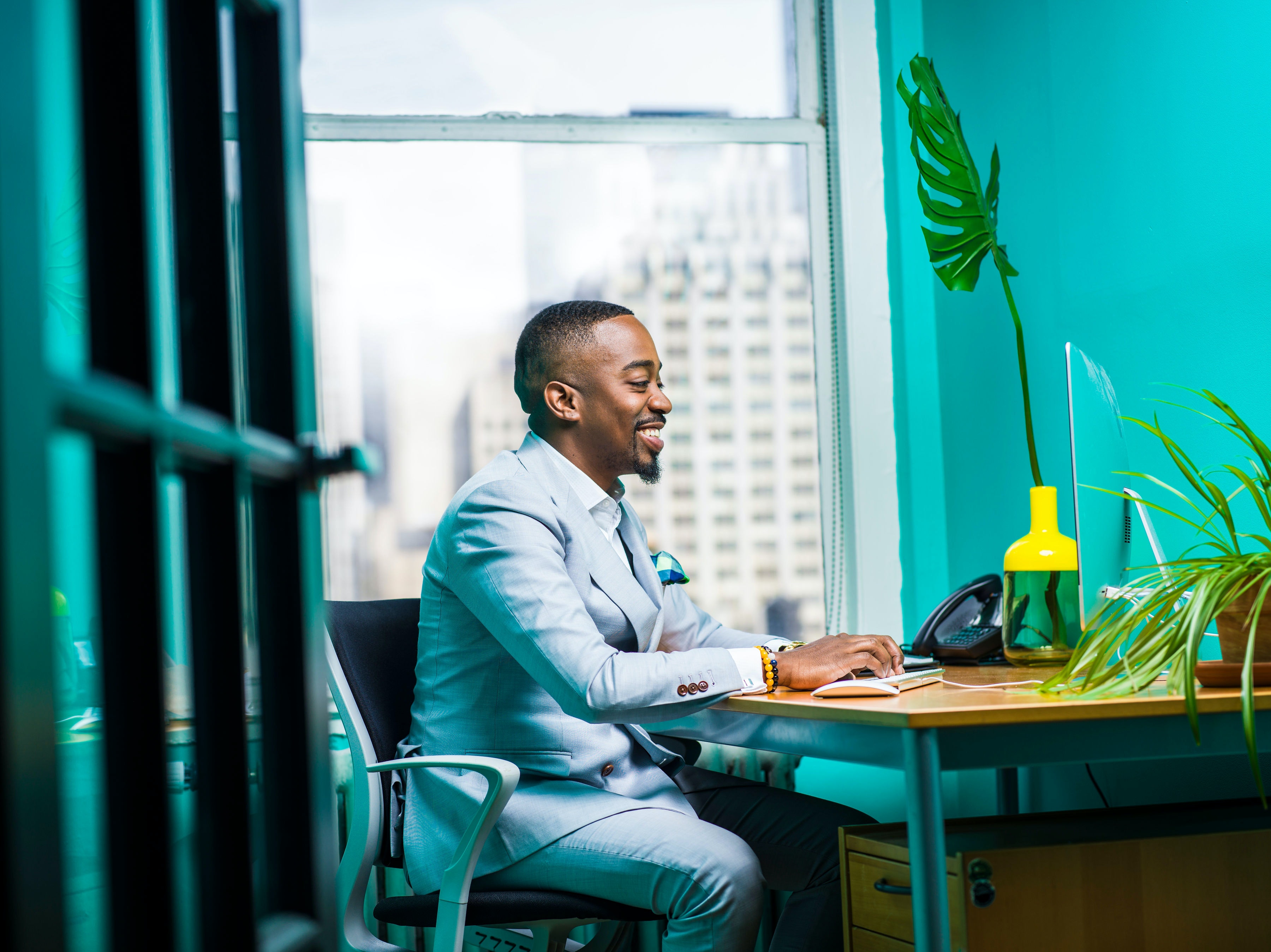 man in suit in teal turquoise office online computer