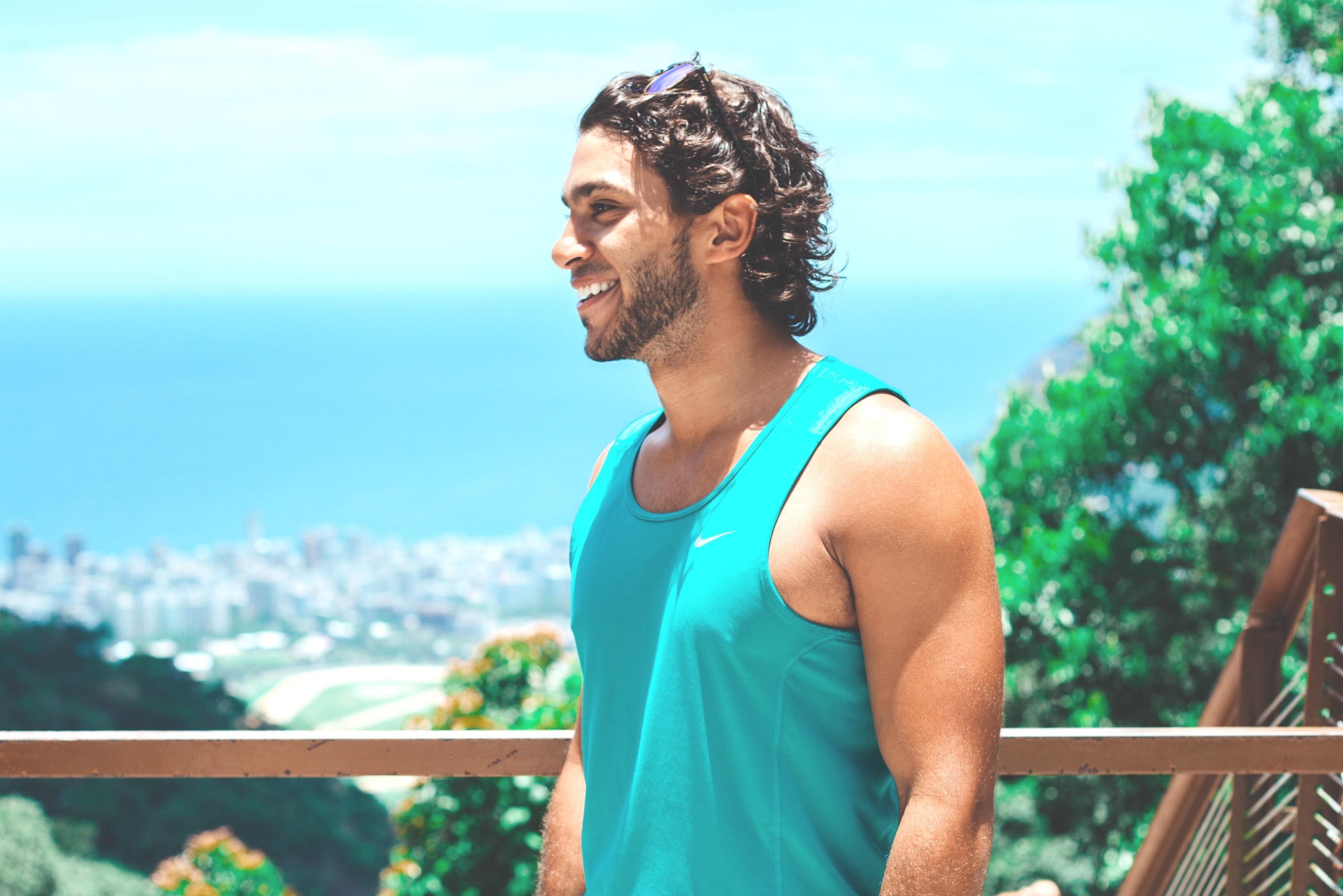 smiling man in turquoise sleeveless shirt