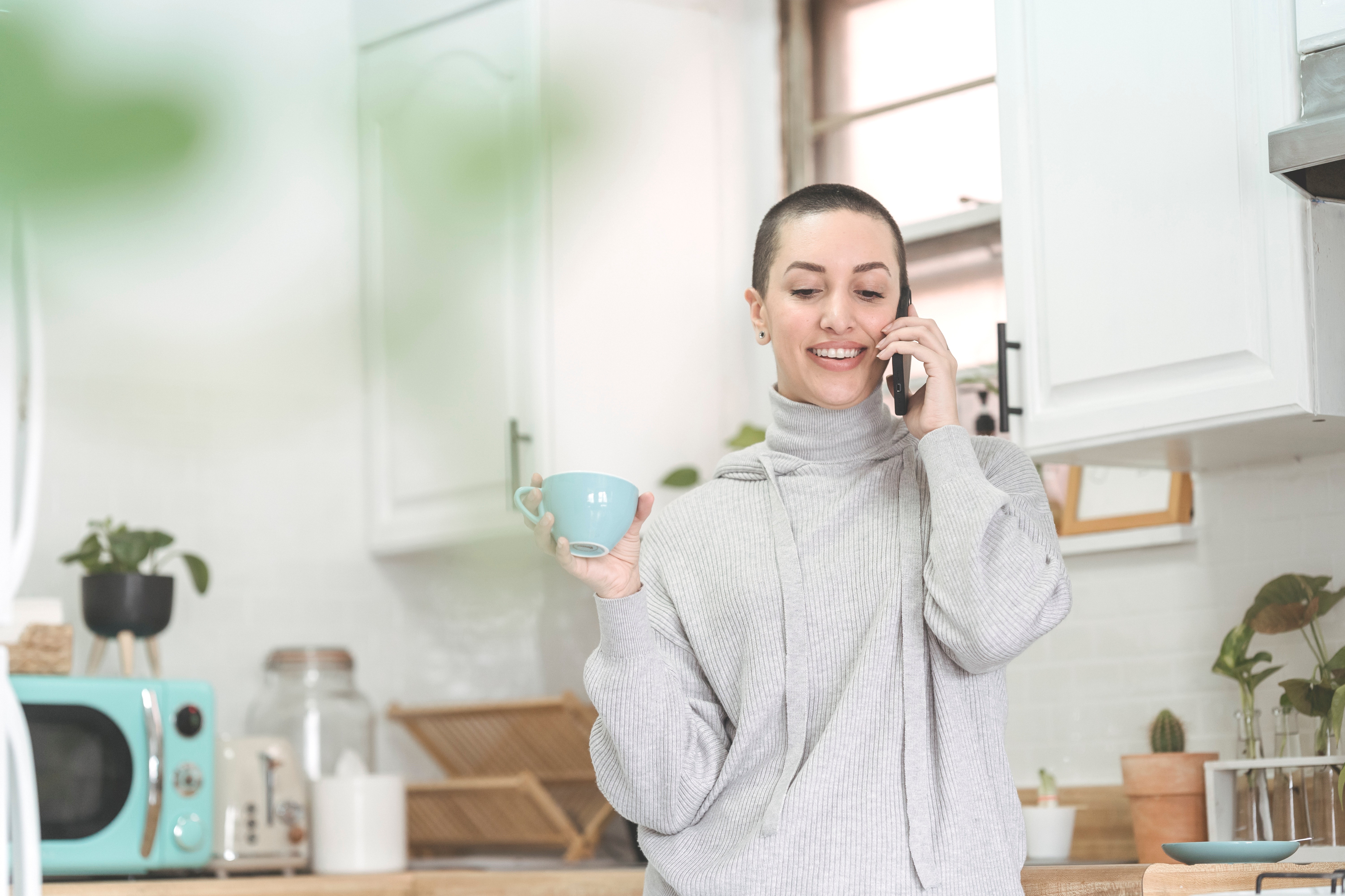 woman on phone holding a teal coffee mug
